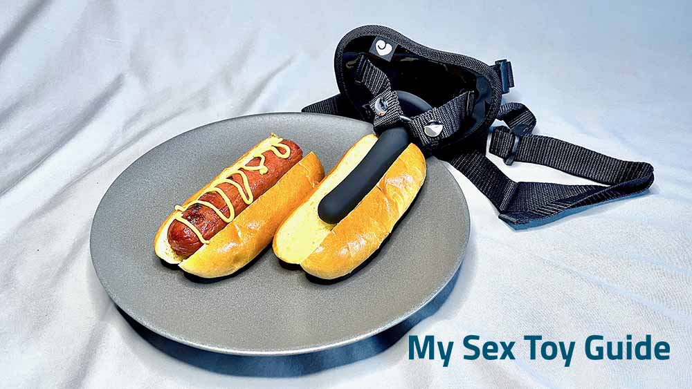 Lovehoney Beginner’s Unisex Strap-On with a hot dog bun for size reference.